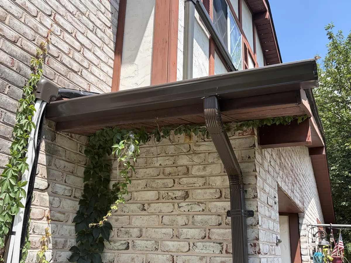 New brown seamless gutter and downspout on a brick Tudor home by LV Roofing & Siding